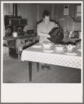 Mrs. Wardlow getting dinner after church in her basement dugout home. Dead Ox Flat, Malheur County, Oregon