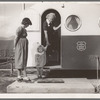 Young mother brings her child to the trailer clinic on the day when the doctor will be in camp to examine some of the children. FSA (Farm Security Administration) mobile camp. Merrill, Klamath County, Oregon