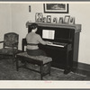 Lois Madsen playing the piano in the home of her father, Harry Madsen, owner-operator of three hundred and sixty acre farm near Dickens, Iowa