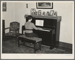 Lois Madsen playing the piano in the home of her father, Harry Madsen, owner-operator of three hundred and sixty acre farm near Dickens, Iowa