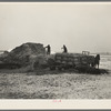 Hired hands pitching straw in wagon to be used for bedding for hog house. H. Madsen farm near Dickens, Iowa