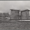 Open corn crib method of storing corn, with stacks of fodder in background. Emmet County, Iowa