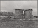 Open corn crib method of storing corn, with stacks of fodder in background. Emmet County, Iowa