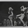 Three female dancers perform a step, while in the background male dancers as the Jets assume a menacing pose in a scene from the film version of West Side Story