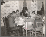 7:10 p.m. Tip Estes and family eating dinner. The day's work has been finished. Tip Estes has washed up and dinner is served