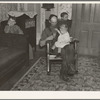 7:40 p.m. Tip Estes, hired man, with the youngest of his nine children. After dinner the family sits around until 8:00 or 8:30, when they go to bed. There is no reading matter in the house