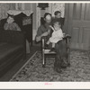 7:40 p.m. Tip Estes, hired man, with the youngest of his nine children. After dinner the family sits around until 8:00 or 8:30, when they go to bed. There is no reading matter in the house