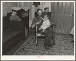 7:40 p.m. Tip Estes, hired man, with the youngest of his nine children. After dinner the family sits around until 8:00 or 8:30, when they go to bed. There is no reading matter in the house