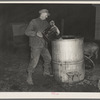 6:40 p.m. Tip Estes, hired man near Fowler, Indiana, filling an automatic hog waterer. He has to carry eighty gallons of water fifty yards to fill this
