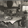 Buckboard Charlie reading the American Legion monthly in the living room of his shack near Iron River, Michigan