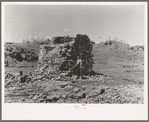 Mr. Henrickson, one of the old timers at Mansfield, Michigan, standing at the base of the former one hundred foot smokestack of an abandoned iron mine. This is one of the few recognizable remains of the mine