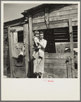 Mother and child in front of woodshed. Gibbs City, Michigan
