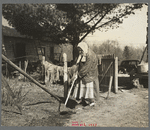 An old lady hoeing her garden on her small farm near Gibbs City, Michigan