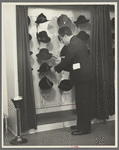 Mr. Leefer, manager of the millinery department, arranges hats in the New York City showroom