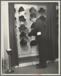 Mr. Leefer, manager of the millinery department, arranges hats in the New York City showroom