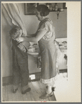 Mrs. Rustan combing her young son's hair. Rustan brothers' farm, Dickens, Iowa. Note running water