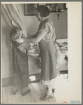 Mrs. Rustan combing her young son's hair. Rustan brothers' farm, Dickens, Iowa. Note running water