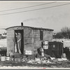 Mrs. Charles Benning sweeping steps of shack in "Shantytown," Spencer, Iowa