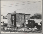 Mrs. Charles Benning sweeping steps of shack in "Shantytown," Spencer, Iowa