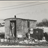 Mrs. Charles Benning sweeping steps of shack in "Shantytown," Spencer, Iowa