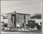 Mrs. Charles Benning sweeping steps of shack in "Shantytown," Spencer, Iowa