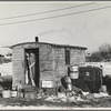 Mrs. Charles Benning sweeping steps of shack in "Shantytown," Spencer, Iowa