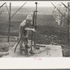 Late afternoon. One of Tip Estes' sons disconnects pipe from the windmill pump. Fowler, Indiana