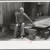 Farmer sitting on rotted porch of his old home, Southeast Missouri farms