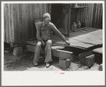 Farmer sitting on rotted porch of his old home, Southeast Missouri farms