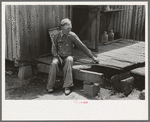 Farmer sitting on rotted porch of his old home, Southeast Missouri farms