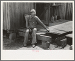 Farmer sitting on rotted porch of his old home, Southeast Missouri farms