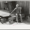 Farmer sitting on rotted porch of his old home, Southeast Missouri farms
