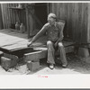 Farmer sitting on rotted porch of his old home, Southeast Missouri farms