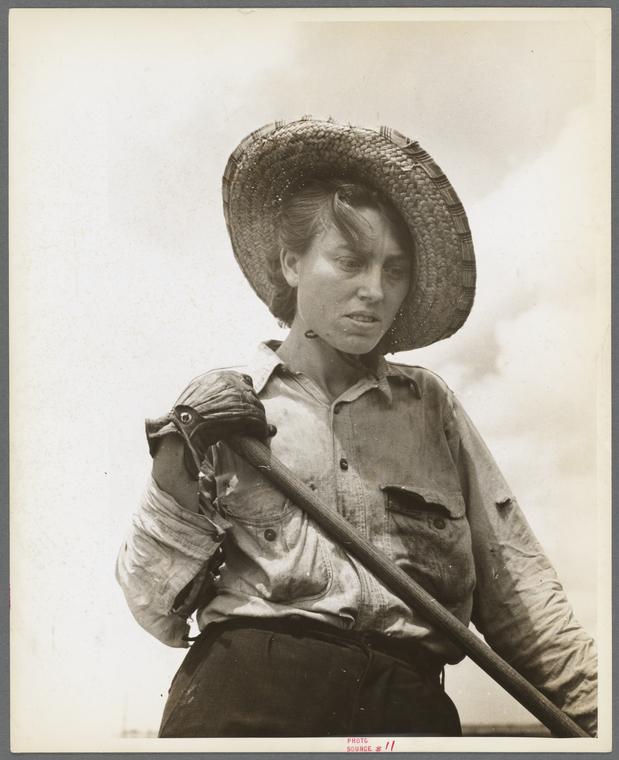 weary-looking woman in a field leaning on a hoe