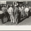 Group of farmers at auction with auction assistants resting on canes used for guiding livestock, Sikeston, Missouri