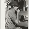 Farmer eating peach at livestock auction, Sikeston, Missouri