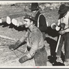 Lumberjack adjusting loading chain around log at camp near Effie, Minnesota