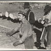 Lumberjack adjusting loading chain around log at camp near Effie, Minnesota