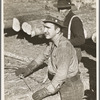 Lumberjack adjusting loading chain around log at camp near Effie, Minnesota