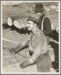 Lumberjack adjusting loading chain around log at camp near Effie, Minnesota