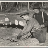 Lumberjack adjusting loading chain around log at camp near Effie, Minnesota