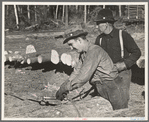 Lumberjack adjusting loading chain around log at camp near Effie, Minnesota