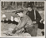 Lumberjack adjusting loading chain around log at camp near Effie, Minnesota