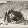 Herman Gerling dipping water from a spring to fill the barrels on his truck. North Dakota