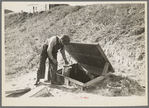 Herman Gerling dipping water from a spring to fill the barrels on his truck. North Dakota