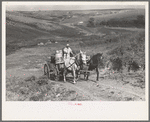 Mrs. Olie Thompson driving wagon loaded with water barrels. North Dakota
