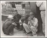 Farmers squatting on sidewalk, Caruthersville, Missouri