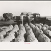 Bags of threshed rice in the foreground, with loading operations in middleground, Crowley, Louisiana