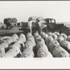 Bags of threshed rice in the foreground, with loading operations in middleground, Crowley, Louisiana