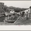 Unloading oysters from small boats, Olga, Louisiana. Note length of canal leading out to Gulf